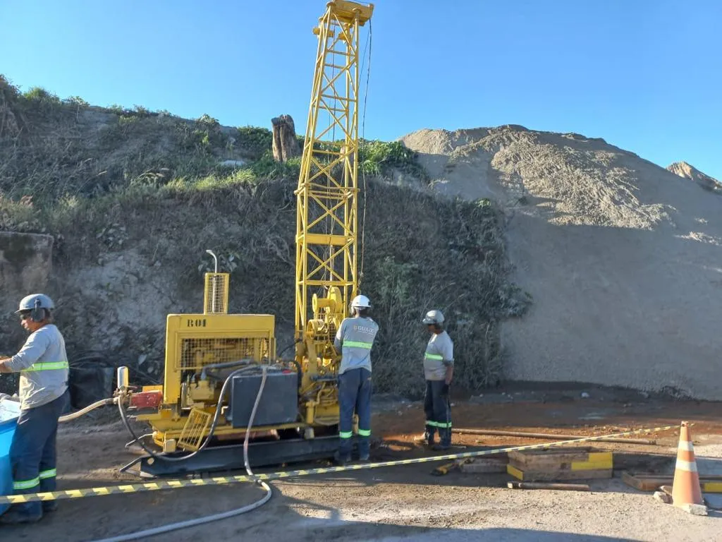 Equipe operando sonda rotativa ao lado de um talude